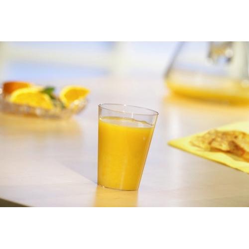 Ein Starpak 40 Trinkbecher, PS 0,1 l Ø 5,5 cm · 7,5 cm glasklarer Einwegbecher ist mit Orangensaft gefüllt auf einem hellen Tisch. Im Hintergrund sind Orangenscheiben und ein Krug – ideal für Partys und Veranstaltungen.