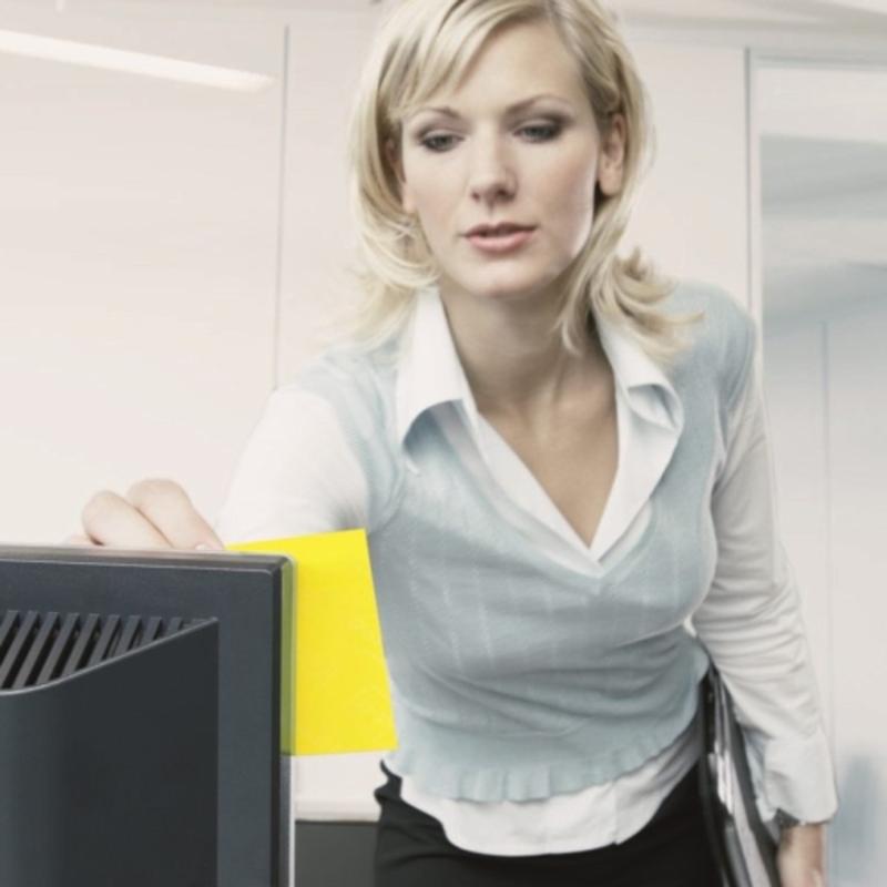 Bizneswoman w nowoczesnym biurze przykleja kostkę notatek samoprzylepnych Post-it® 636-B, żółtą, 76 mm x 76 mm, od 3M Deutschland GmbH na swój monitor, trzymając jednocześnie dokumenty. Samoprzylepne karteczki służą jako pomoc w przypominaniu.