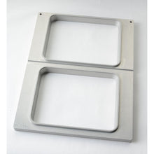 Die Duni GmbH Kassette DF15/25 für CPET Schalen 960-1500 ml - 2-nutzig ist ein rechteckiger Metallrahmen mit zwei vertikal angeordneten Öffnungen, gebürstetem Finish und abgerundeten Kanten - perfekt für die Aufbewahrung von CPET Schalen auf jeder weißen Oberfläche.