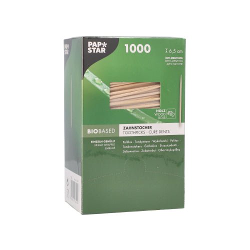 Zielono-białe pudełko PAPSTAR GmbH wykałaczki okrągłe 6,5 cm, drewno o smaku mentolowym, karton z dozownikiem z 1000 sztuk jest wielojęzycznie oznakowane i ma okienko, w którym widoczne są drewniane wykałaczki o smaku mentolowym.