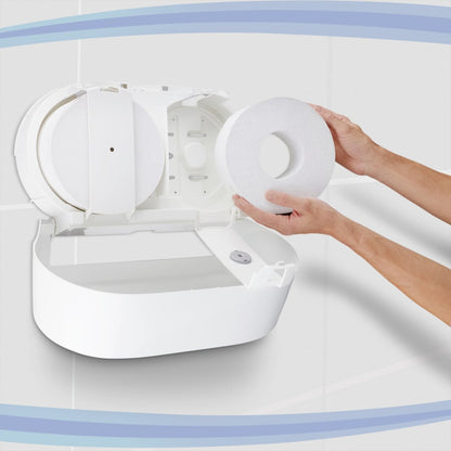 Osoba ładuje dozownik papieru toaletowego Aquarius™ - centralny / biały / Jumbo firmy Kimberly-Clark GmbH, z otwartą pokrywą. Białe wyłożone płytkami ściany i niebieskie krzywe w tle podkreślają praktyczny centralny design dozownika.