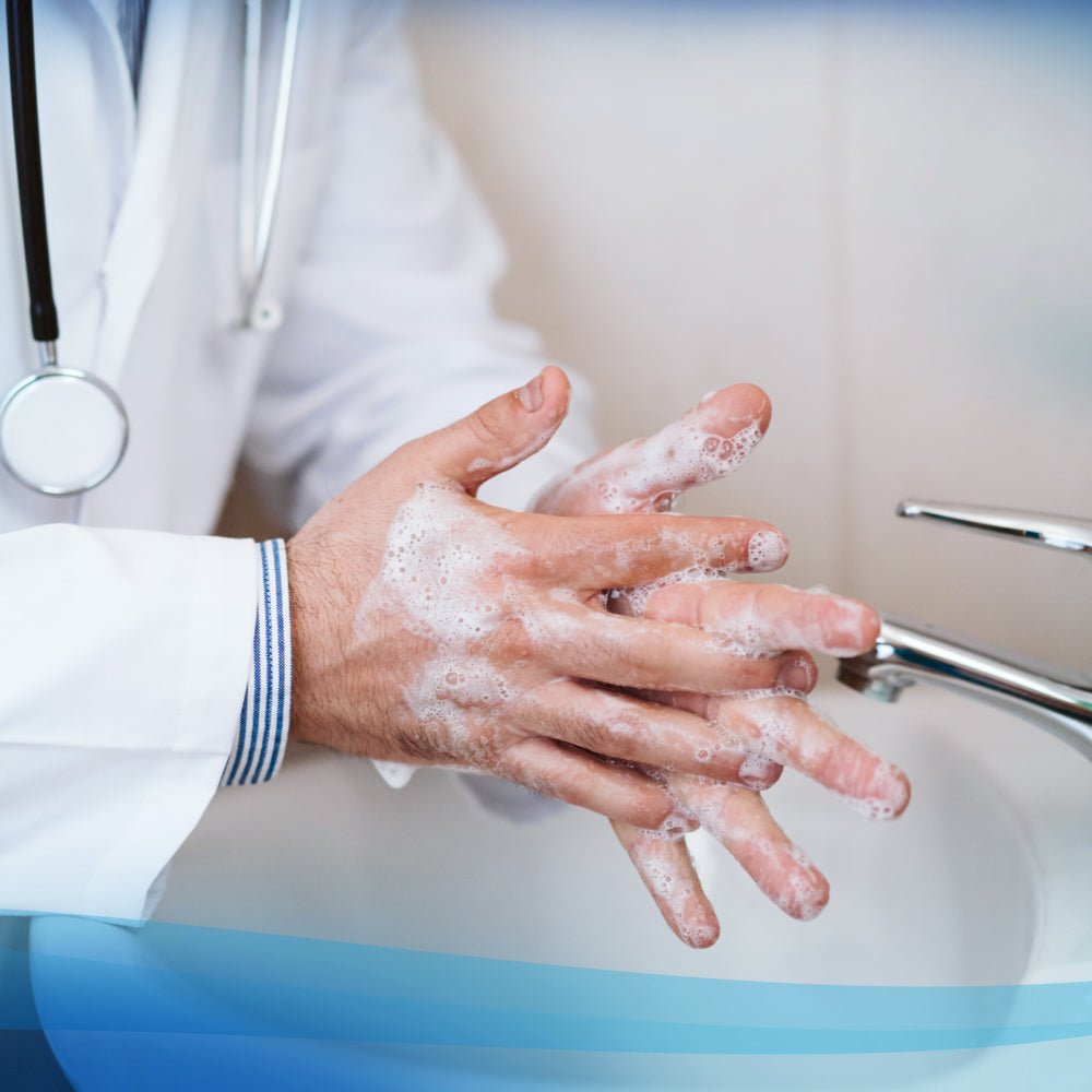 Osoba w białym fartuchu laboratoryjnym używa Scott® Control™ Antybakteryjny Środek do Mycia Rąk od Kimberly-Clark GmbH przy umywalce i tworzy pianę. Stetoskop na jej szyi podkreśla konieczność higienicznego mycia rąk w służbie zdrowia.