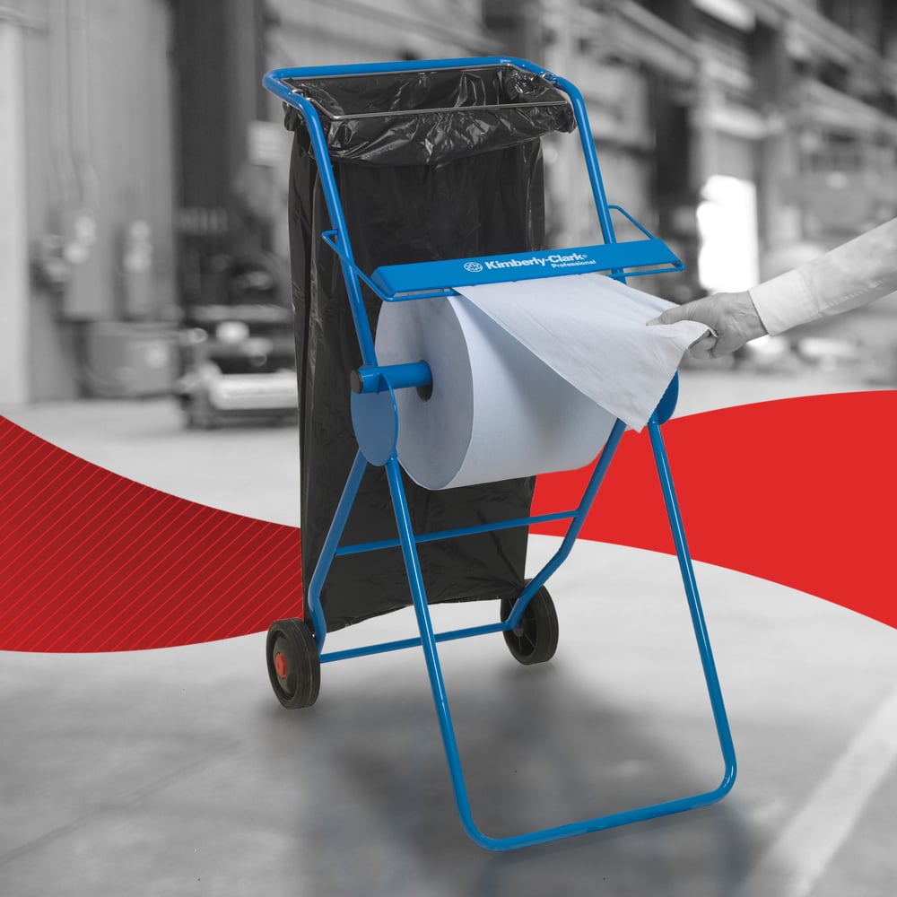 Osoba używa papierowego ręcznika WypAll® L30 od Kimberly-Clark GmbH z bardzo szerokiej rolki na niebieskim dozowniku z workiem na śmieci w środowisku przemysłowym - idealny do zadań czyszczenia przemysłowego.