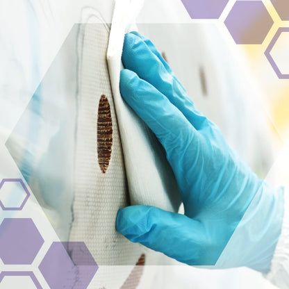 Ręka w niebieskiej rękawiczce czyści brązowe plamy z białej powierzchni przy użyciu Kimberly-Clark GmbH Kimtech® Science Chusteczek Precyzyjnych (200 arkuszy, białe), idealnych do delikatnych powierzchni. Sześciokątne grafiki pojawiają się w rogach obrazu.