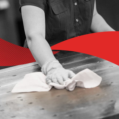 Osoba w koszuli z krótkim rękawem wyciera dużą metalową powierzchnię chusteczką, prawdopodobnie WypAll® X60 General Clean z BRAG™ Box (41,80 cm x 28,30 cm) firmy Kimberly-Clark GmbH; obraz jest głównie czarno-biały z mocną czerwoną przekątną pośrodku.