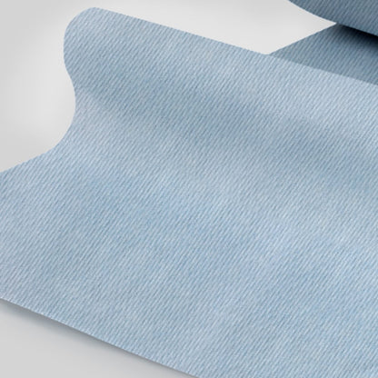 Zbliżenie ręcznika papierowego WypAll® L10 do powierzchni - duża rolka (38,00 cm x 23,50 cm) od Kimberly-Clark GmbH, jasnoniebieski z subtelną diagonalną strukturą pasków, częściowo rozwinięty na płaskiej powierzchni.