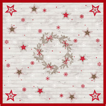 Obrus Dunicel 84x84cm Cozy Winter od Duni GmbH przedstawia wieniec z gałęzi i czerwonych kokardek, z czerwonymi i beżowymi gwiazdami oraz płatkami śniegu na jasnym drewnianym tle. Idealna dekoracja świąteczna, dostępna w opakowaniach po 20 sztuk.