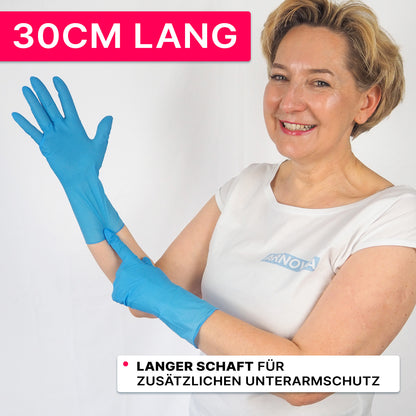 Osoba w białej koszuli i niebieskich rękawicach nitrylowych firmy ARNOWA GmbH uśmiecha się i wskazuje na 30 cm mankiet. Na różowym banerze widnieje napis „30CM DŁUGOŚCI”, podkreślający, że rękawice ARNOMED NITRIL BLUE XTRA LONG oferują dodatkową ochronę przedramienia.