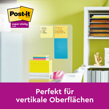 Na szklanej ścianie przyklejone są karteczki Post-it® Super Sticky Meeting Notes od 3M w różnych kolorach (203 x 153 mm, 70 arkuszy/blok, 3 bloki), idealne do powierzchni pionowych. W tle materiały biurowe i książki na biurku.