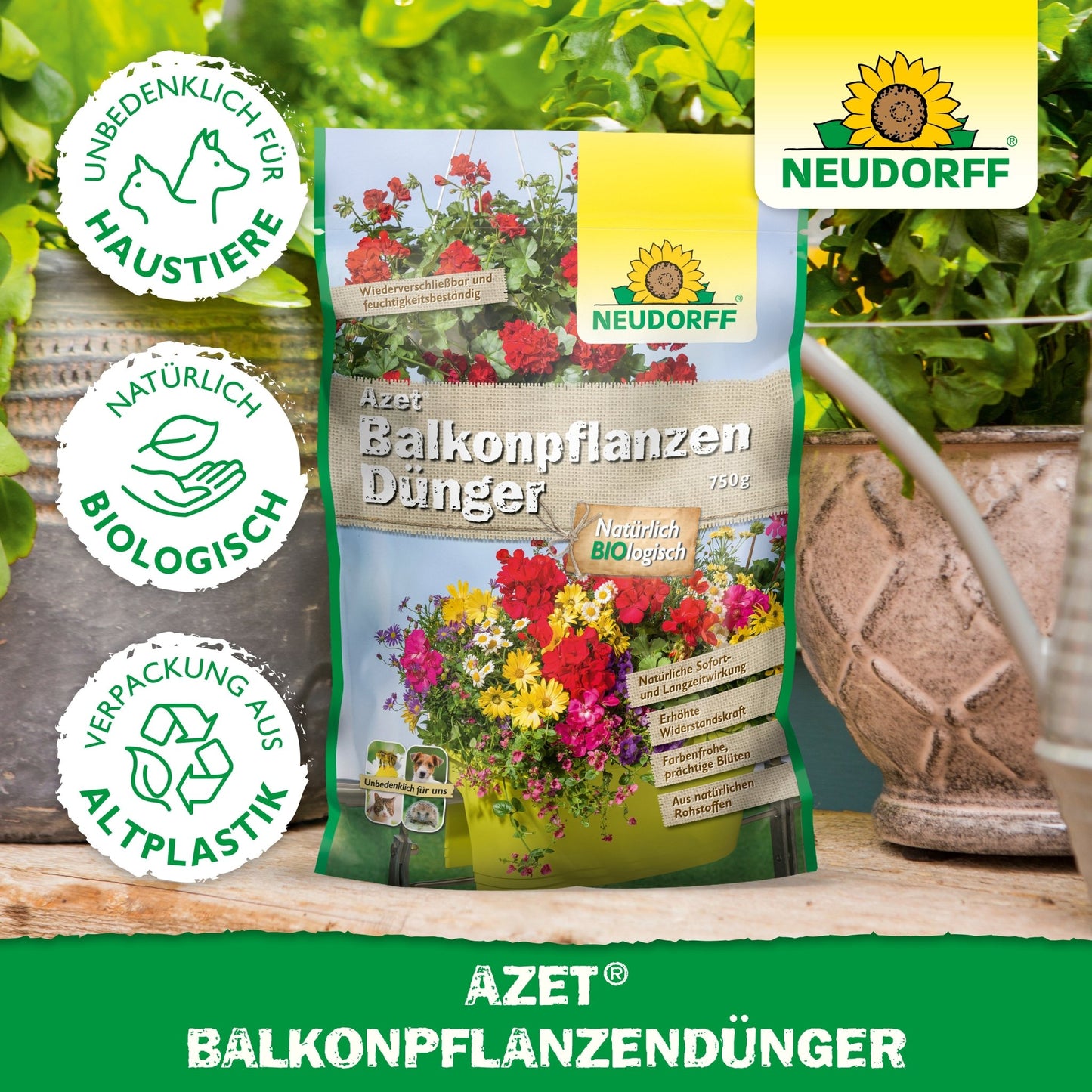 Torebka Azet BalkonpflanzenDünger z Neudorff Shop stoi na stole między roślinami doniczkowymi a skrzynkami balkonowymi. Opakowanie pokazuje kwiaty, tekst i symbole ochrony zwierząt, biologiczne składniki i opakowania z bioplastiku.