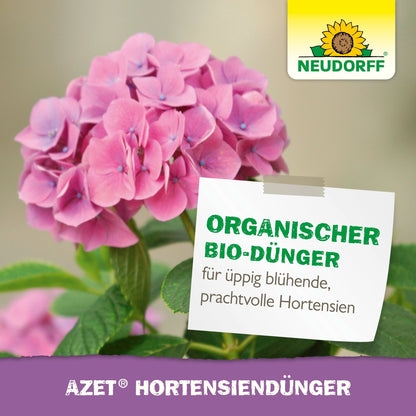 Różowa hortensja z zielonymi liśćmi. Na etykiecie widnieje napis "Organiczny specjalny nawóz do bujnie kwitnących, wspaniałych hortensji". Logo Neudorff Shop (słonecznik) w prawym górnym rogu. Tekst na dole: "Płynny nawóz do hortensji Azet".