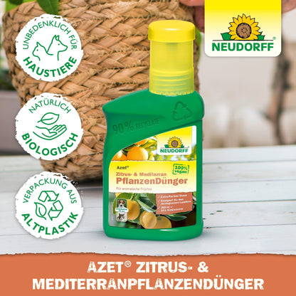 Zielona butelka Neudorff Shop Azet Zitrus- & MediterranpflanzenDünger płynny stoi na drewnie. Trzy symbole pokazują, że jest odpowiedni dla zwierząt domowych, wykonany z recyklingowanego plastiku i biodegradowalny. Idealny dla roślin śródziemnomorskich, takich jak oleandry. Tekst jest po niemiecku.