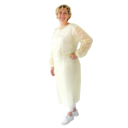 Osoba stoi uśmiechnięta z ręką na biodrze i nosi jednorazowy fartuch ochronny ARNOMED Virendichter (żółty, powłoka PP/PE, 10 sztuk) firmy ARNOWA GmbH na białych spodniach i butach na prostym białym tle.