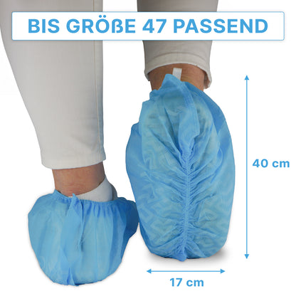 Eine Person trägt blaue ARNOMED ABS Schuhüberzieher der ARNOWA GmbH über einer weißen Hose; diese rutschfesten Einweg-Schuhüberzieher passen bis Größe 47 und messen ca. 40×17 cm, wie durch Pfeile dargestellt. Packung: 100 Stück.
