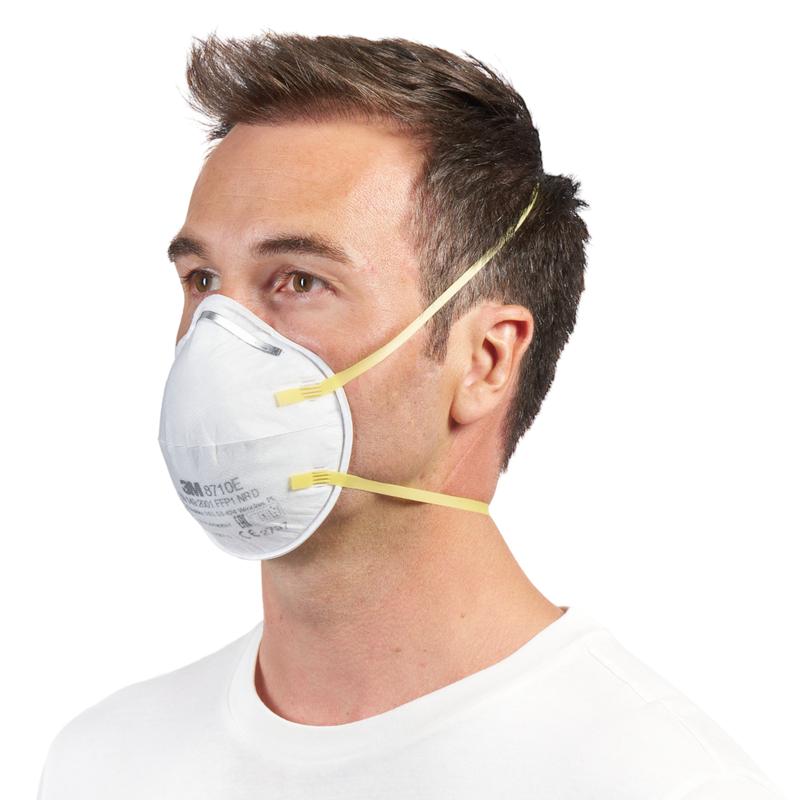 Mężczyzna z krótkimi brązowymi włosami nosi maskę cząsteczkową 3M™ 8710E FFP1 (od 3M Deutschland GmbH) z żółtymi paskami i bez zaworu na nosie i ustach, w połączeniu z prostą białą koszulą na białym tle.