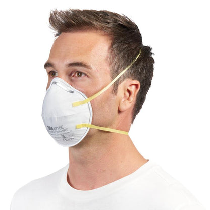 Mężczyzna z krótkimi brązowymi włosami nosi maskę cząsteczkową 3M™ 8710E FFP1 (od 3M Deutschland GmbH) z żółtymi paskami i bez zaworu na nosie i ustach, w połączeniu z prostą białą koszulą na białym tle.