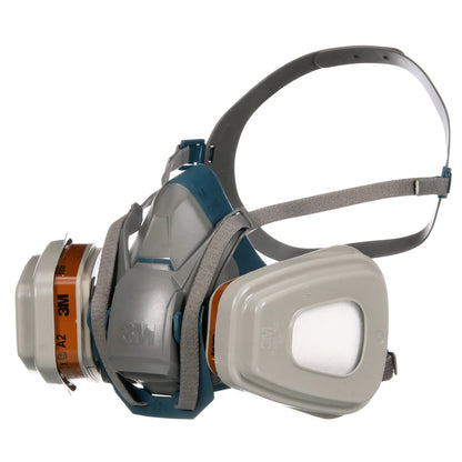 Maska ochronna 3M™ Quick Latch 6502QLKIT-1 firmy 3M Deutschland GmbH z wymiennymi filtrami A2P3 (1x6502, 2x6055, 2x5935, 2x501) pokazuje regulowane szare paski i szaro-niebieską obudowę maski z widocznym logo.