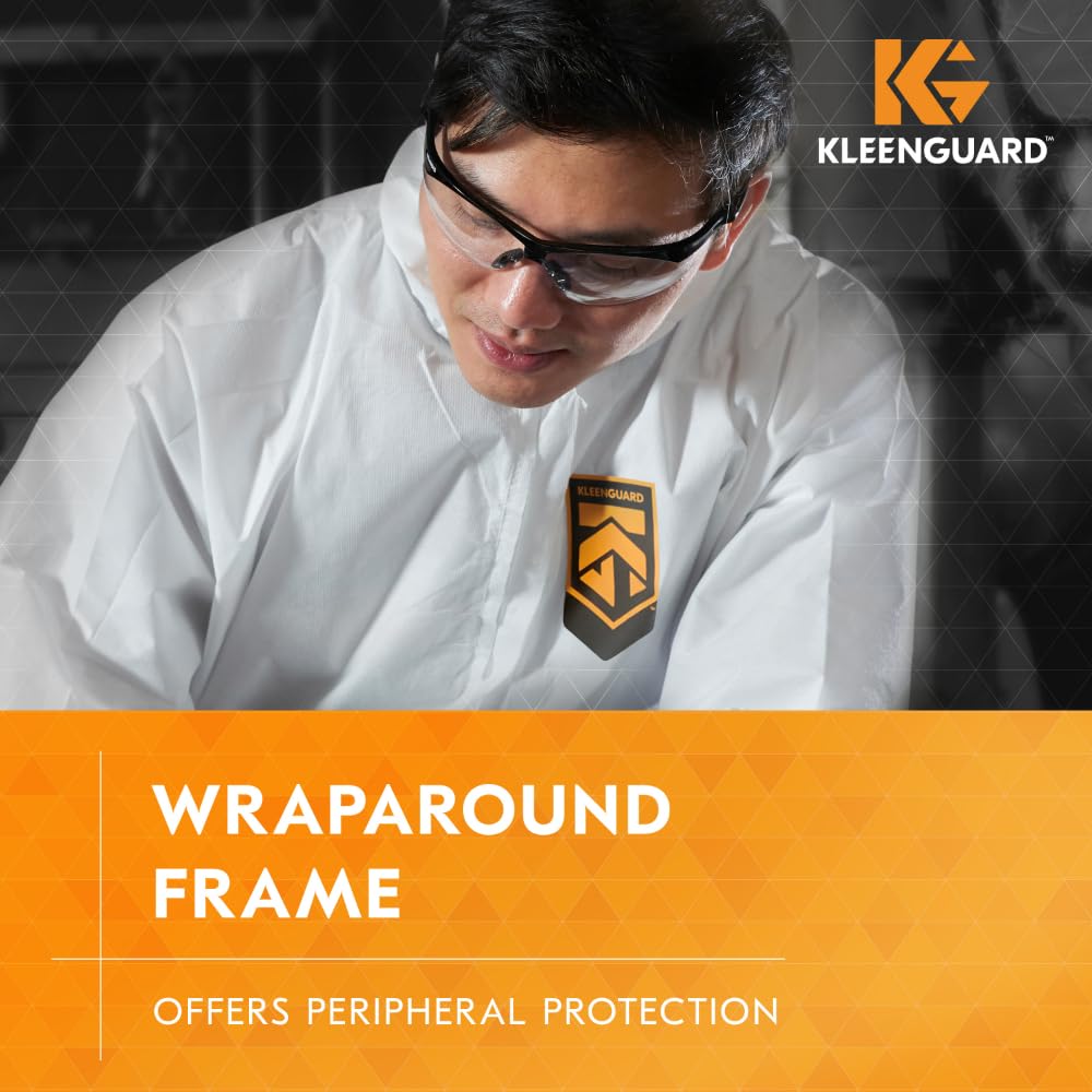 Eine Person in einem weißen Anzug mit dem KleenGuard-Logo trägt die KleenGuard® V30 Nemesis™ Schutzbrille von Kimberly-Clark; Text: "Wraparound Frame - Offers Peripheral Protection" und hebt die Beschlagfrei-Beschichtung hervor.