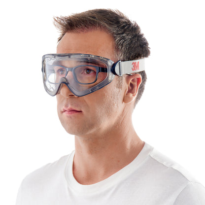 Mężczyzna z krótkimi brązowymi włosami i prostą białą koszulką nosi na białym tle okulary ochronne 3M™ 2890, zapieczętowane, z przezroczystą soczewką od 3M Deutschland GmbH z białą gumką z napisem "3M.