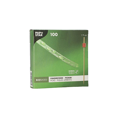 Zielone pudełko "PAPSTAR 100 wykałaczek do fingerfood" od PAPSTAR GmbH zawiera 100 bambusowych wykałaczek o długości 9 cm każda. Biodegradowalne opakowanie przedstawia wykałaczkę z czerwoną końcówką, idealną do serwowania szaszłyków fingerfood na każdej imprezie.