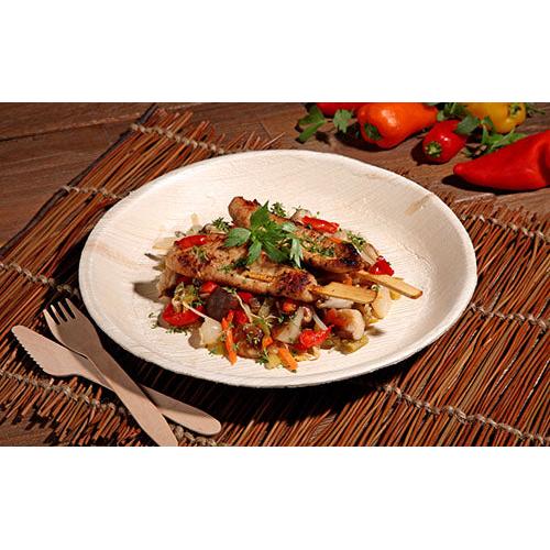 Gegrilltes Fleischspießchen mit gemischtem Gemüse und Kräutern wird auf einem PAPSTAR 25 Teller, Palmblatt „pure“ rund von der PAPSTAR GmbH, serviert, mit umweltfreundlichem Einweggeschirr und bunten Paprikaschoten und Gemüse im Hintergrund.