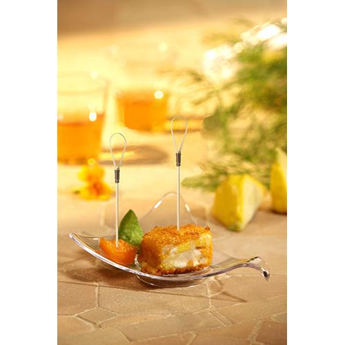 Nahaufnahme eines Vorspeisentellers mit zwei mundgerechten Snacks auf PAPSTAR 100 Fingerfood - Picker von PAPSTAR GmbH, hergestellt aus Bambus Holz und garniert mit Früchten, auf einer beigen Fläche mit Getränken und Kräutern im Hintergrund.