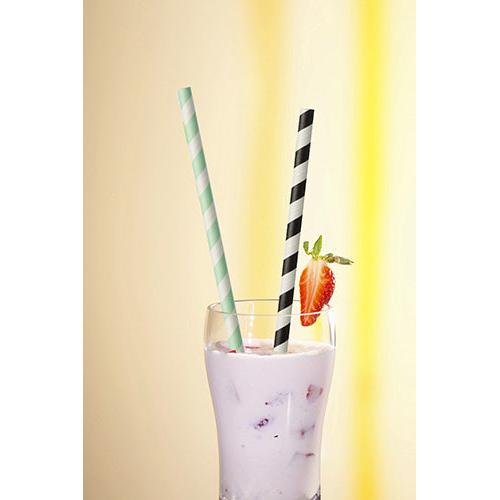 W szklance z różowym milkshake'em, lodami, kawałkami owoców i truskawkową dekoracją znajdują się dwie PAPSTAR 100 papierowe słomki (Ø 6 mm, od PAPSTAR GmbH), jedna w zielone paski i jedna w czarne paski.