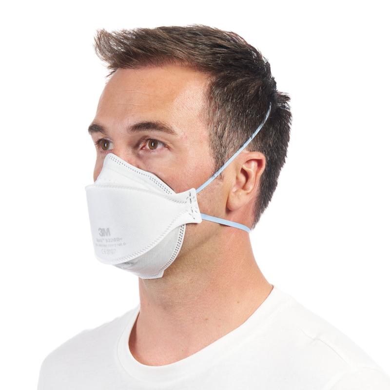 Mężczyzna w prostym białym koszuli nosi maskę cząsteczkową 3M™ Aura™ Komfort 9320+ FFP2 bez zaworu od 3M Deutschland GmbH, z dwoma paskami na głowę i lekko skierowaną w lewo.