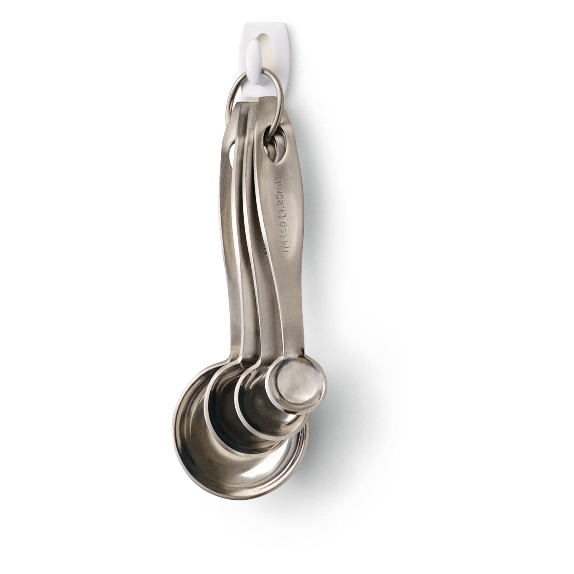 Vier Messlöffel aus rostfreiem Stahl ruhen auf einem Metallring, der an einem weißen Command™ Mini-Haken 17006 von 3M Deutschland GmbH hängt, der an einer weißen Wand vor einem weißen Hintergrund angebracht ist.