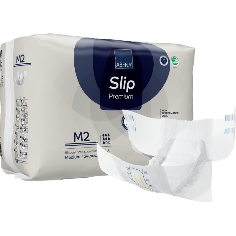 Za rozłożoną pieluchą znajduje się opakowanie ABENA Slip Premium od Abena Re-Seller GmbH, rozmiar M2. Na opakowaniu jest napisane, że zawiera 24 średnie slipy do niezawodnej ochrony przed nietrzymaniem moczu.