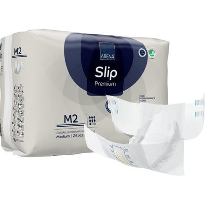 Za rozłożoną pieluchą znajduje się opakowanie ABENA Slip Premium od Abena Re-Seller GmbH, rozmiar M2. Na opakowaniu jest napisane, że zawiera 24 średnie slipy do niezawodnej ochrony przed nietrzymaniem moczu.