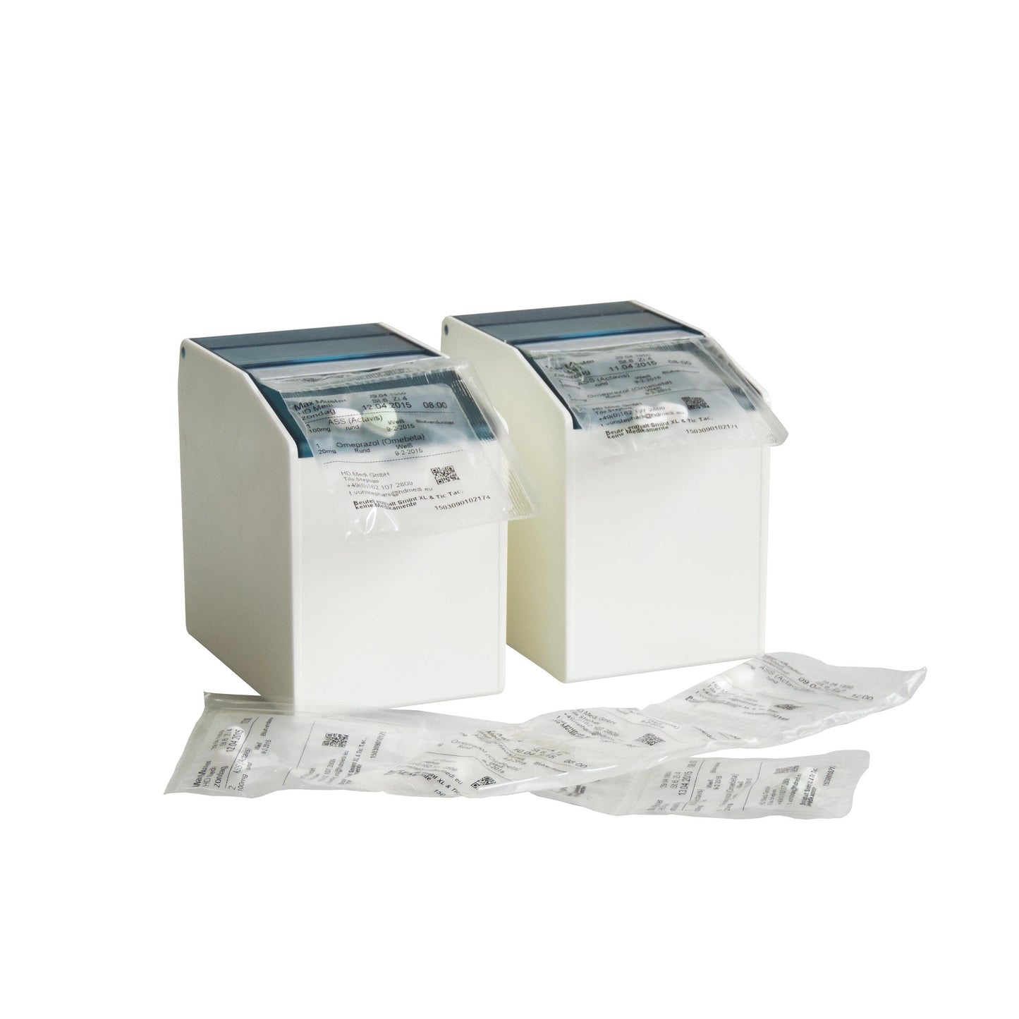 Zwei weiße Novocal Blisterbox-Spender (1 flexible Frontklappe, 2 rückseitige Magnetstreifen, 80 mm, 1 Packung) nehmen versiegelte Medikamentenpackungen auf, mit zusätzlichen Packungen kleiner Produkte auf weißer Fläche vor einfarbigem Hintergrund.