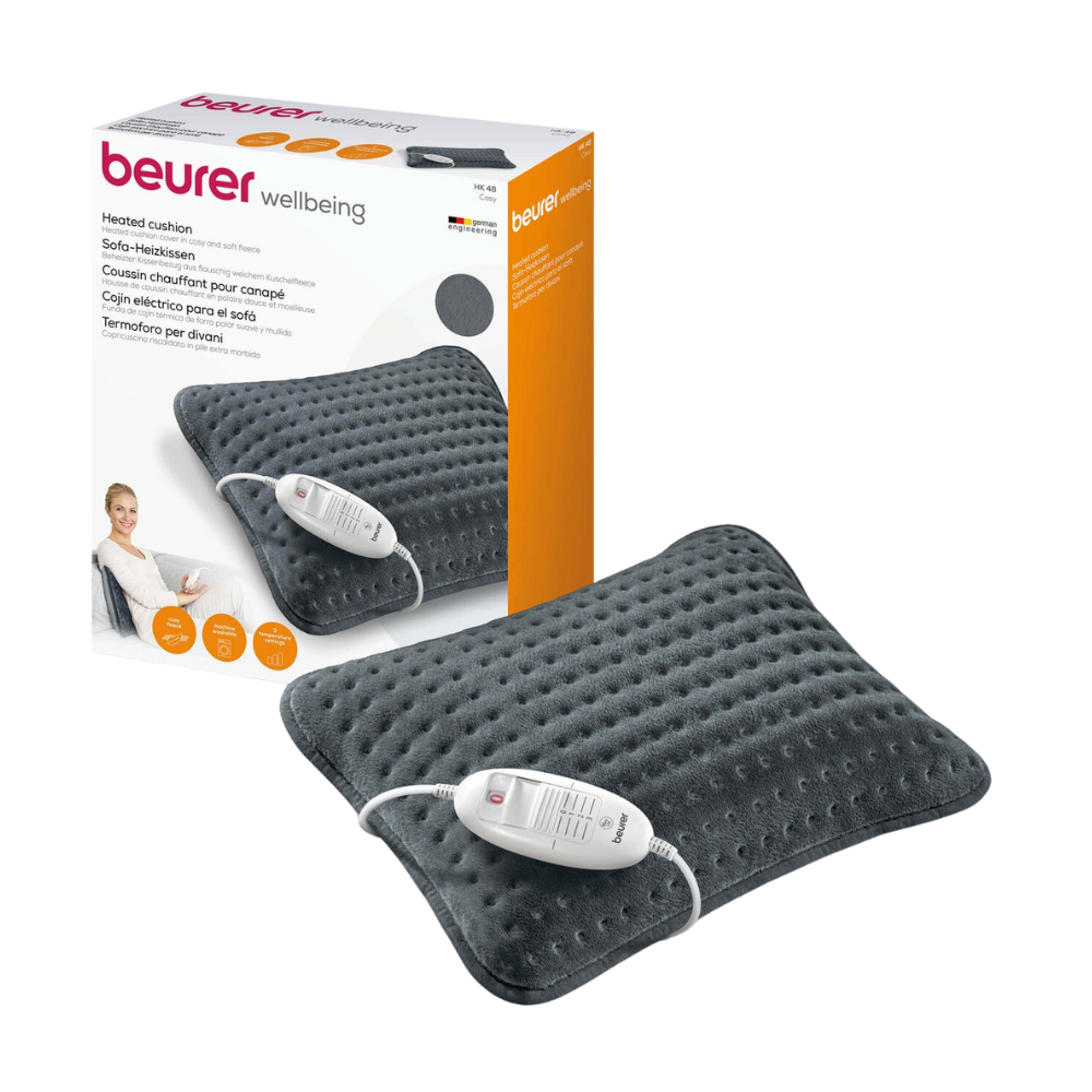 Obraz Beurer HK 48 poduszki grzewczej na sofę Cosy. Ciemnoszara, strukturalna poduszka grzewcza firmy Beurer GmbH posiada zintegrowaną jednostkę sterującą i zaawansowany system bezpieczeństwa. Za poduszką znajduje się pudełko z markami produktów, obrazkami i opisami.