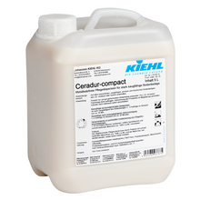 Eine 5-Liter-Flasche Johannes Kiehl KG Ceradur-compact, eine metallsalzfreie Pflegedispersion für stark saugfähige Bodenbeläge, kommt in weißem Kunststoff mit einem Griff und deutschem Etikett. Verkauft in einem Karton mit 2 Flaschen.
