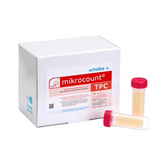 Białe pudełko z napisem „Schülke & Mayr GmbH Mikrocount® TPC, podłoże hodowlane | Opakowanie (20 sztuk)”, z logo i opisem produktu, obok którego znajdują się dwie fiolki do badań mikrobiologicznych – jedna z żółtą nakrętką, a druga z przezroczystą nakrętką.