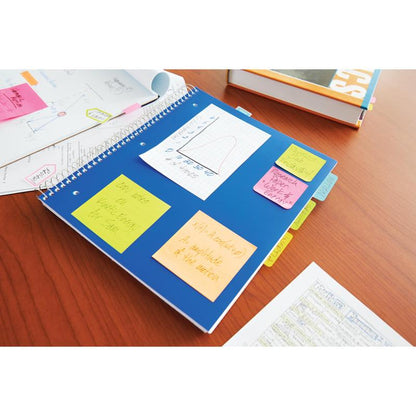 Niebieski zeszyt w spirali z karteczkami Post-it® 3M Deutschland GmbH w różnych kolorach neonowych (38x51 mm, 100 arkuszy/blok, 3 bloki/opakowanie) leży na drewnianym stole, obok papierów i podręcznika szkolnego.