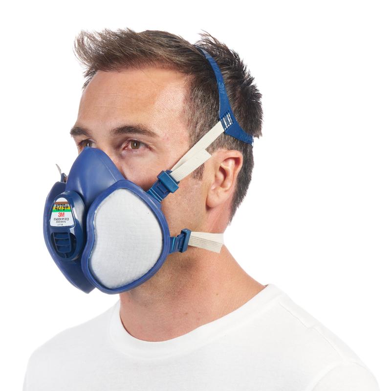 Mężczyzna z krótkimi brązowymi włosami i białą koszulą jest widoczny z profilu. Nosi maskę ochronną 3M™ z zintegrowanymi filtrami od 3M Deutschland GmbH, która ma niebieski design i regulowane paski na głowę.