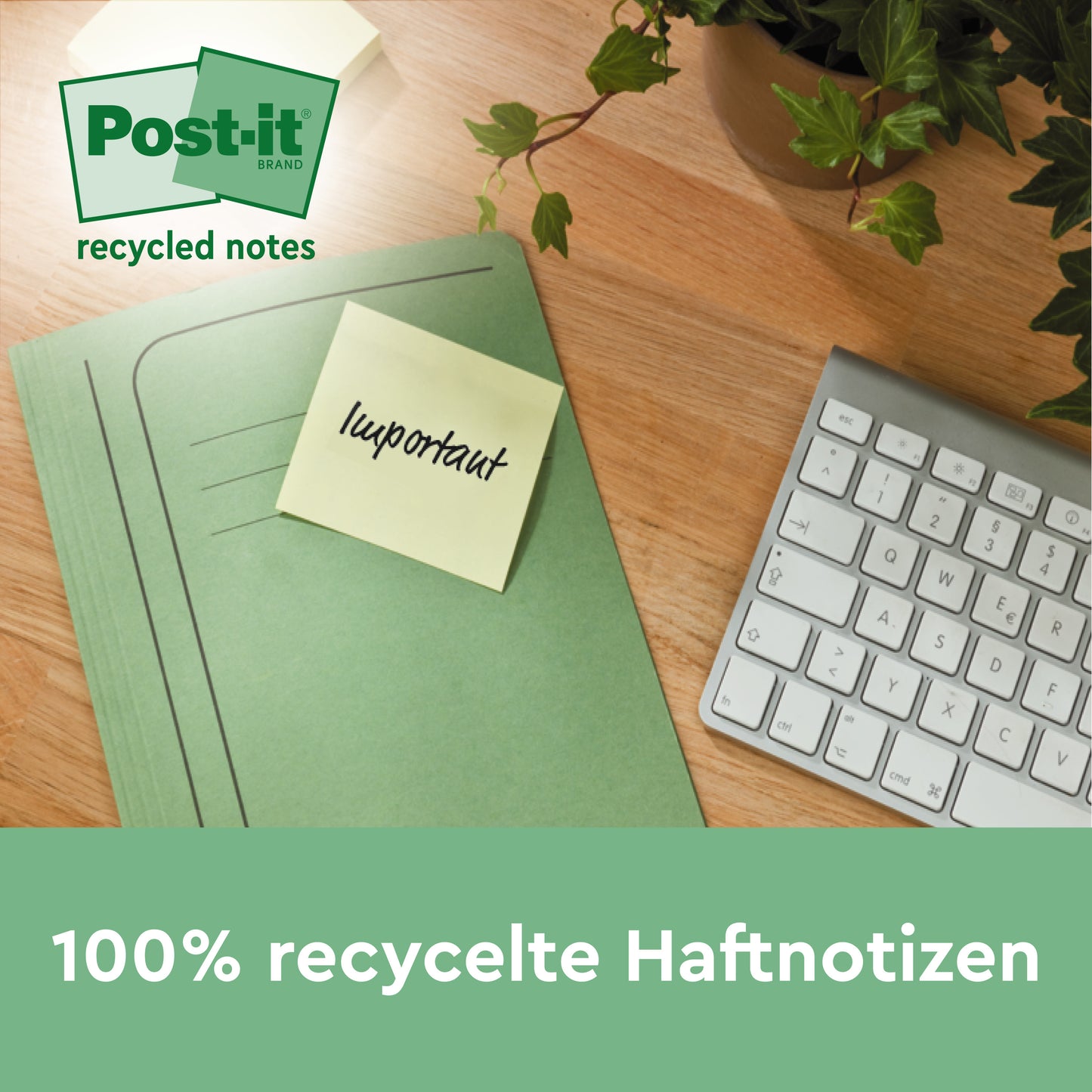 Zielony segregator z żółtymi Post-it® Recycling Notes, żółte, 76x127mm, 100 kartek/blok od 3M Deutschland GmbH leży na drewnianym biurku obok białej klawiatury i rośliny. Kartki są w 100% PEFC (SGSCH-PEFC-COC-110078) i przyjazne dla środowiska.