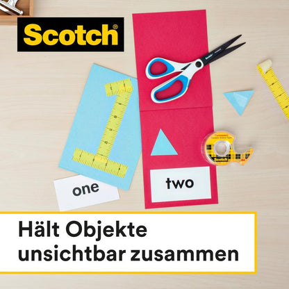 Na stole leżą nożyczki, miarka, opakowanie uzupełniające dwustronnej taśmy klejącej Scotch® (2 rolki, 12 mm x 6,3 m) od 3M Deutschland GmbH oraz kolorowy papier z wyciętymi kształtami. Tekst brzmi: "Łączy obiekty niewidocznie."