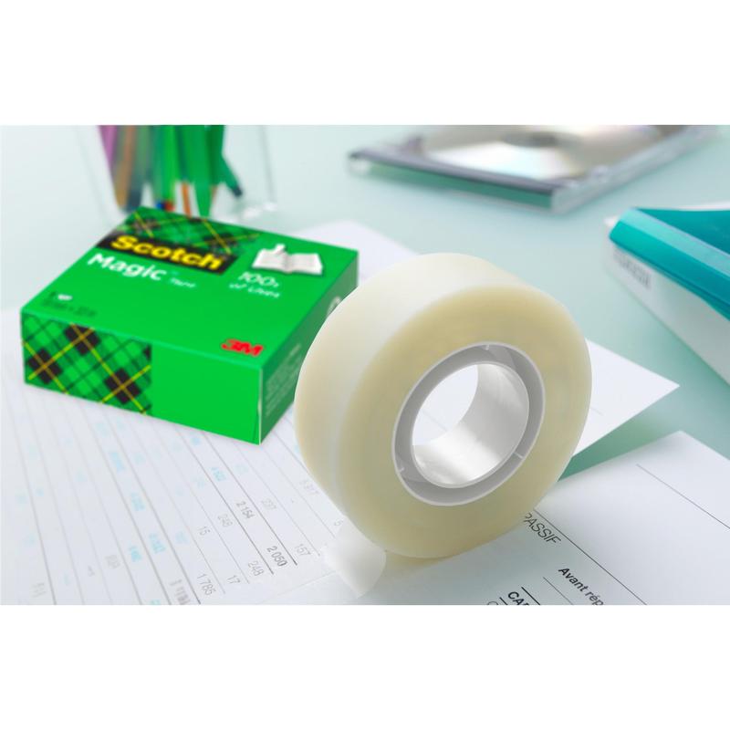 Rolka Scotch® Magic™ Invisible Tape (19 mm x 33 m) od 3M Deutschland GmbH z zestawu promocyjnego z 24 rolkami jest rozwijana na papierze, podczas gdy zielone pudełko z napisem "Zestaw promocyjny, 24 sztuki" stoi wśród materiałów biurowych.